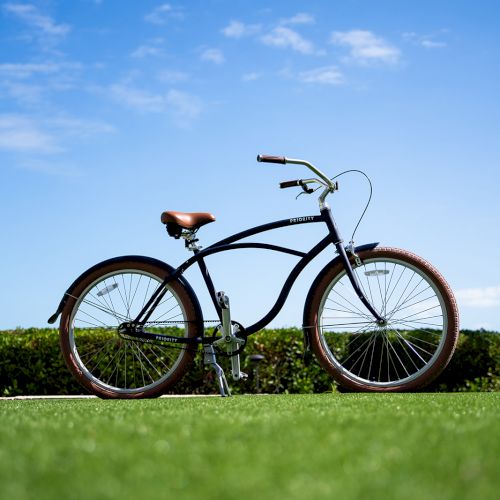 A bicycle stands on a grassy field under a clear blue sky with scattered clouds.