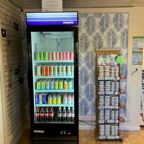 A Norpole vending fridge stocked with drinks, with shelves of salt scrubs on display in a store.