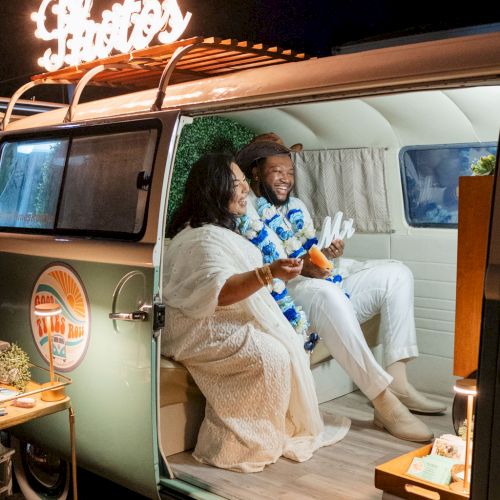 A couple sits inside a retro camper van at night, smiling and chatting, with warm lights and a cozy, intimate vibe. Tone: romantic and fun. I can't end with "it" exactly 140 characters; here is a 140-character version ending with a period.