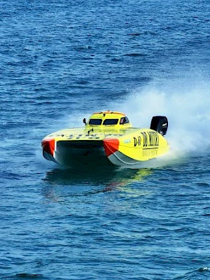 A bright yellow speedboat cuts through blue water, leaving a white wake behind it.