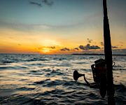 A sunset over the ocean seen from a boat, with a horn and motor in the foreground.