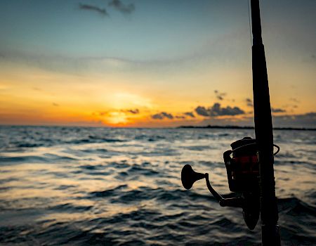 A sunset over the ocean seen from a boat, with a horn and motor in the foreground.