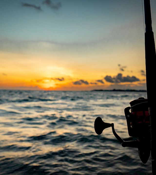 A sunset over the ocean seen from a boat, with a horn and motor in the foreground.